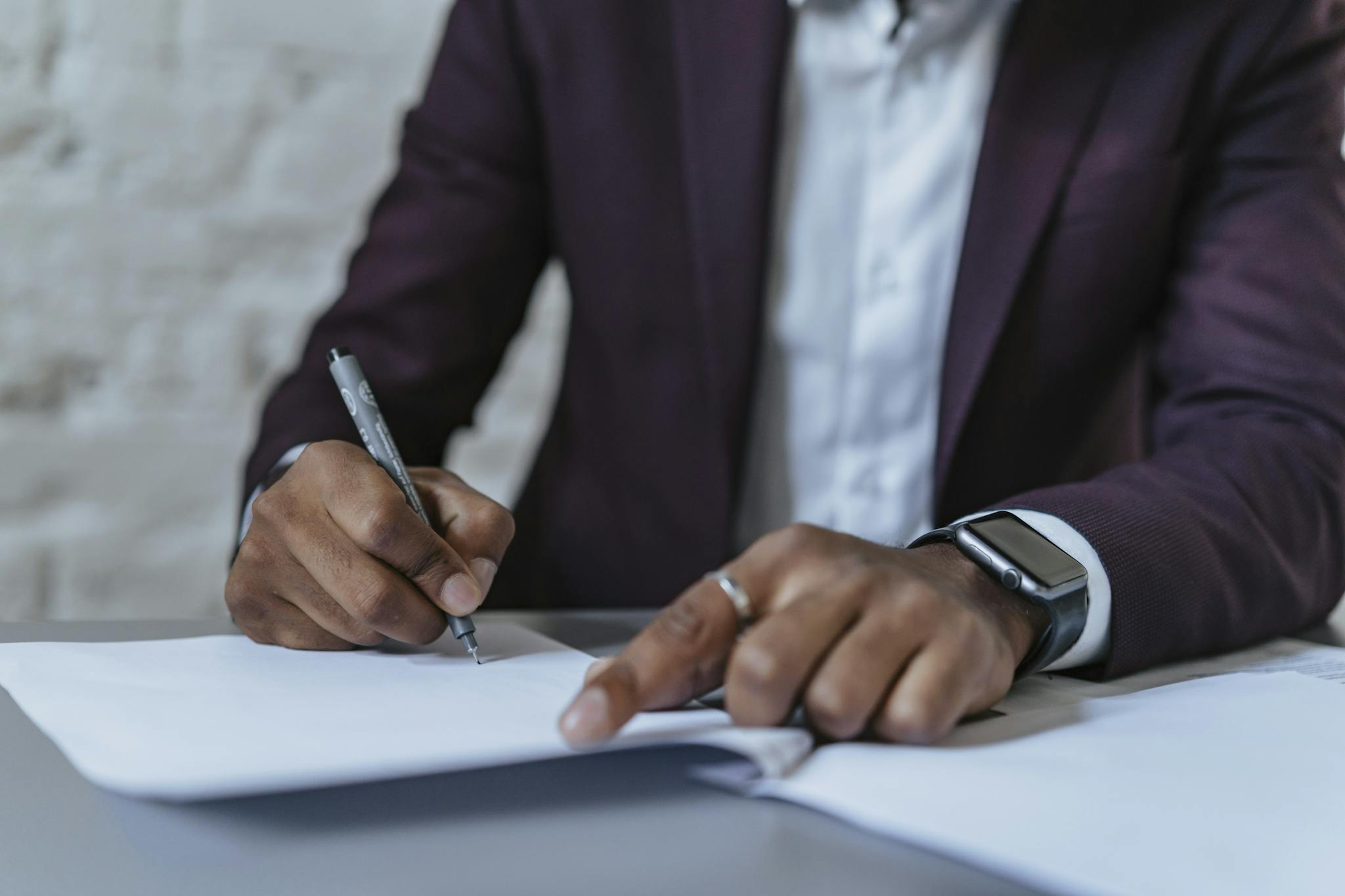 Close-up of a man signing documents in an office. Business-focused and professional environment.