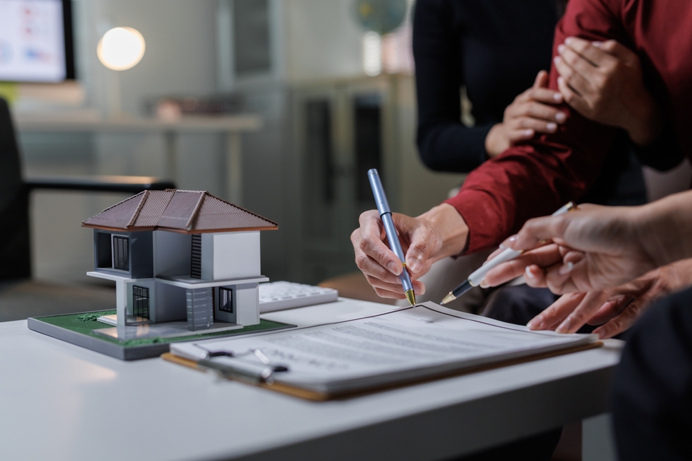 Hands signing real estate purchase contract during Abbotsford property closing with lawyer