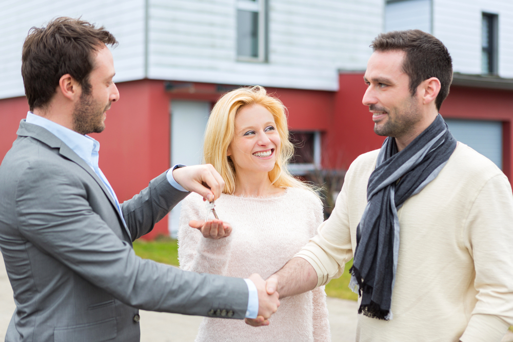 Couple receiving keys from real estate agent after closing on home with Abbotsford real estate lawyer