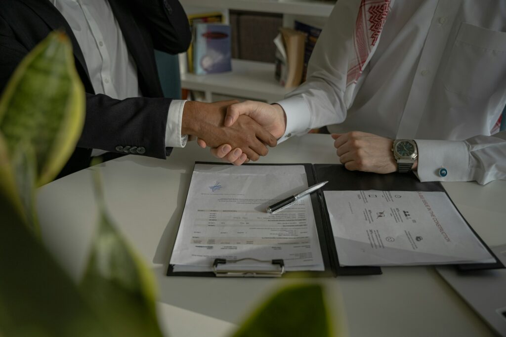 Mortgage broker and lawyer shaking hands over closing paperwork, representing a referral partnership for BC mortgage broker file closings