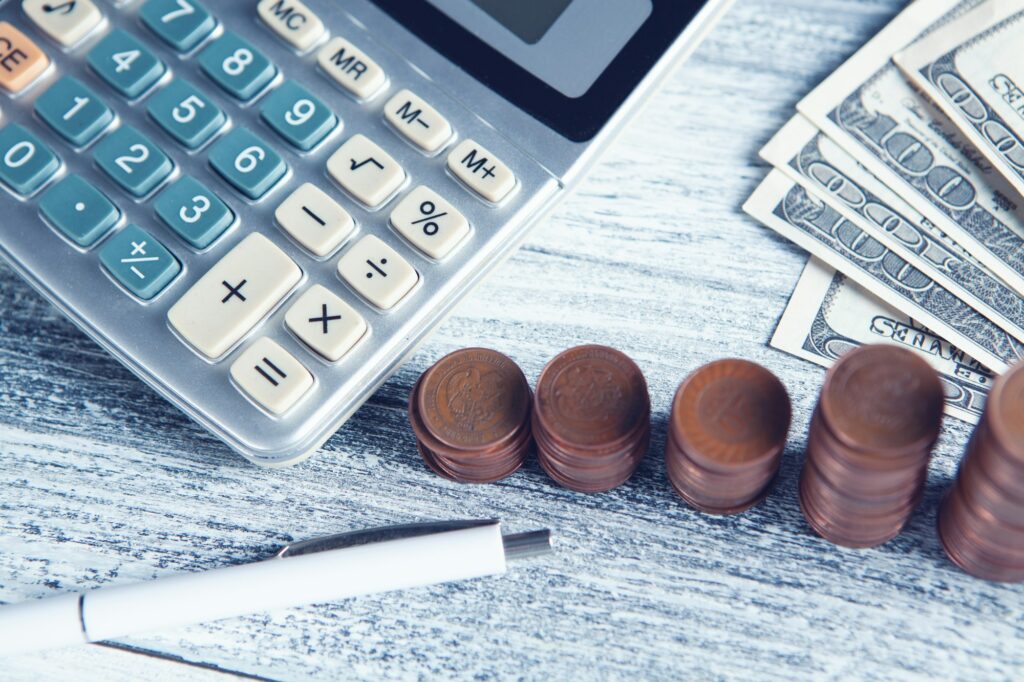 Calculator, pen, and Canadian money on a desk, representing the capital gains tax calculations a seller faces on a BC real estate sale