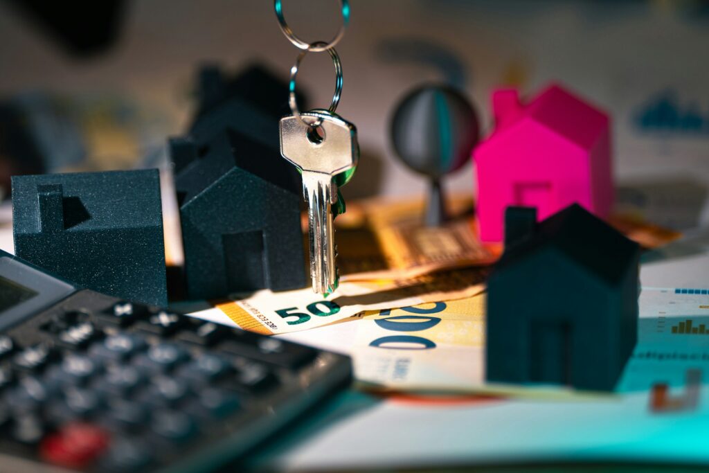 Calculator, house keys, and a model house on a desk, representing the closing day adjustments and Statement of Adjustments in a BC real estate transaction