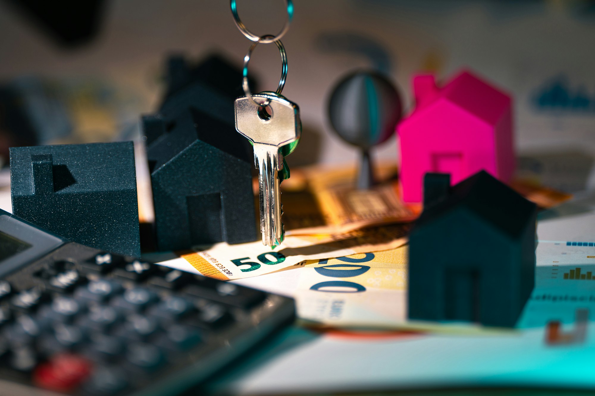 Calculator, house keys, and a model house on a desk, representing the closing day adjustments and Statement of Adjustments in a BC real estate transaction