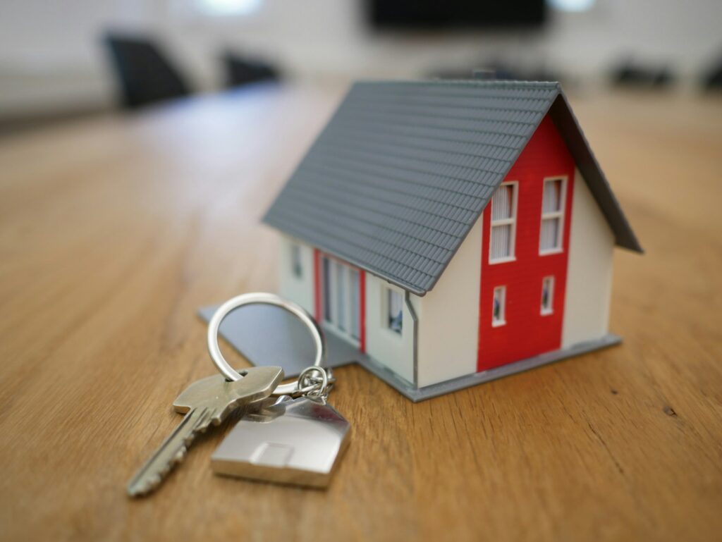 House keys with a small wooden house model on a table, representing a residential real estate closing for a realtor-referred client
