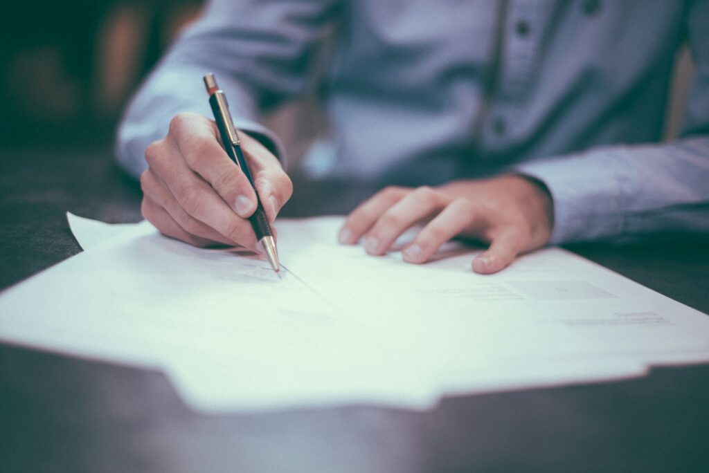 Person completing a property disclosure form on paper, representing the Property Disclosure Statement BC sellers complete in a residential sale